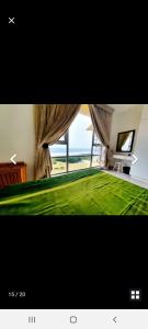 a picture of a bedroom with a green bed and a window at Rockview Holiday Beach Apartment in Hibberdene