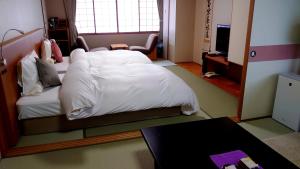 a bedroom with a white bed and a table at Takinoya Bekkan Tamanoyu in Noboribetsu