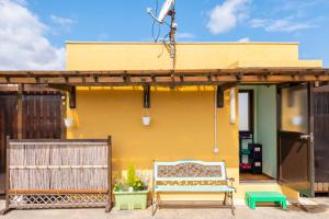 Green Guesthouse في كاجوشيما: منزل اصفر امامه مقعد