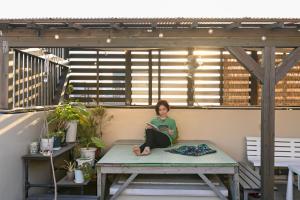 a woman sitting on a bench on a patio at Green Guesthouse in Kagoshima