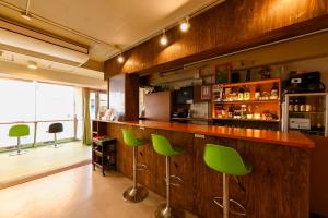 un bar con taburetes verdes en una habitación en Green Guesthouse, en Kagoshima