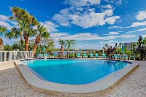a large swimming pool with chairs and palm trees at Bay View Villas #118 in Clearwater Beach