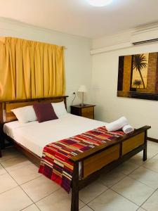 a bedroom with a bed and a yellow curtain at Airlie Beach Apartments in Airlie Beach