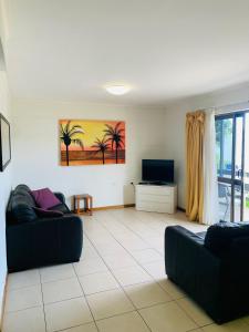 ein Wohnzimmer mit einem Sofa und einem TV in der Unterkunft Airlie Beach Apartments in Airlie Beach