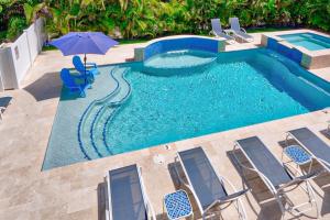 a swimming pool with chairs and an umbrella next to it at Seas the Day in West Palm Beach