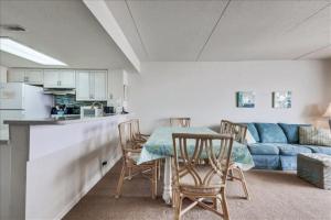 Sea Watch Condos III في آوشين سيتي: غرفة معيشة مع طاولة وكراسي وأريكة