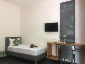 a bedroom with a bed and a desk and a tv at Le Chien Rouge in Lovina