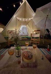 a table with two glasses of wine and a tent at Hoang Indian Tent Camping in Taoyuan