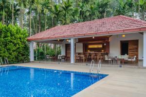 a villa with a swimming pool and a house at StayVista at Tall Silver with Infinity Pool & Breakast in Madikeri