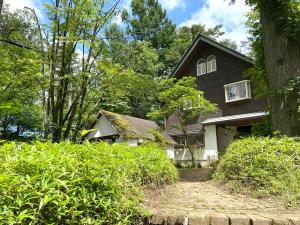 a black and white house with trees and bushes at Pension Razteca in Hakuba