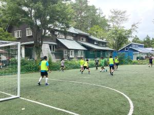 eine Gruppe von Menschen, die auf einem Feld Fußball spielen in der Unterkunft Pension Razteca in Hakuba