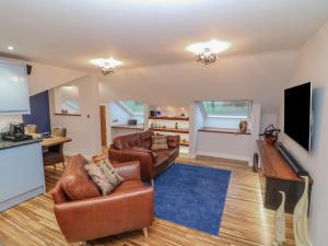 a living room with leather furniture and a flat screen tv at Orchard View Lodge in Exeter
