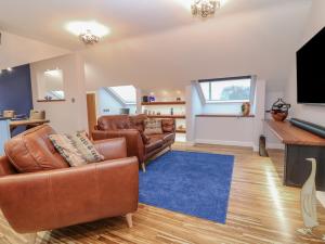 a living room with leather furniture and a flat screen tv at Orchard View Lodge in Exeter