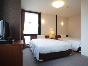 Cette chambre comprend 2 lits et une télévision à écran plat. dans l'établissement Kochi Green Hotel Harimayabashi, à Kōchi