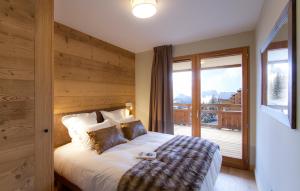 a bedroom with a bed with a wooden wall at Odalys Chalet Chambertin Lodge in Les Deux Alpes