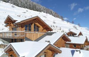 une cabane en rondins dans la neige avec des toits enneigés dans l'établissement Odalys Chalet Chambertin Lodge, à Les Deux Alpes