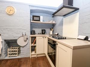 a kitchen with white cabinets and a clock on the wall at 6 Coastal Cottages in Lowestoft