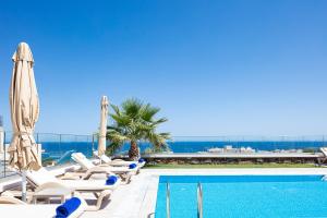 a pool with chaise lounge chairs and an umbrella at Agapi Villas I & II, fairytale seaside retreats, By ThinkVilla in Panormos Rethymno