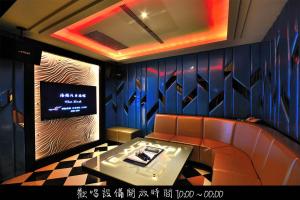 een kamer met een bank en een tv aan de muur bij Hea Duenn Motel in Taichung