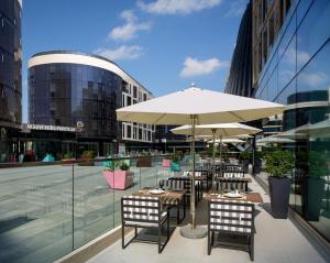 eine Terrasse mit Tischen, Stühlen und einem Sonnenschirm in der Unterkunft Millennium Place Mirdif in Dubai