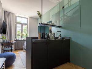 a kitchen with black cabinets and a blue wall at limehome Rottenburg am Neckar Poststraße in Rottenburg