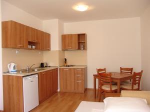 a kitchen with wooden cabinets and a table in a room at Apart Hotel Kasandra in Sunny Beach