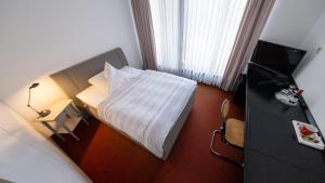 une chambre d'hôtel avec un lit et une télévision dans l'établissement Wissenschaftszentrum Bonn, à Bonn