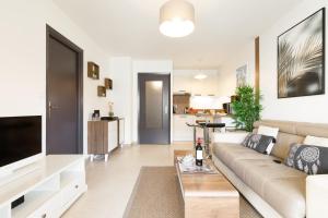 een woonkamer met een bank en een flatscreen-tv bij Le Charme YourHostHelper in Cannes