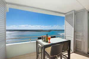 stół i krzesła na balkonie z widokiem na ocean w obiekcie The Grand Apartments w mieście Gold Coast