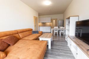 uma sala de estar com um sofá castanho e uma cozinha em Apartmány pod Zakletým - Hotel Říčky em Říčky