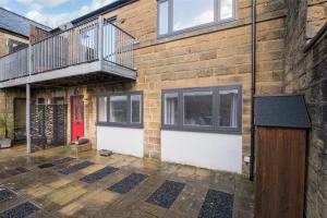 a brick house with a balcony and a wooden door at Immaculate 3 Bed House - Stunning Balcony Views in Matlock