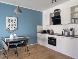 a kitchen with white cabinets and a table and chairs at limehome Trier Nikolaus-Leis-Straße in Trier