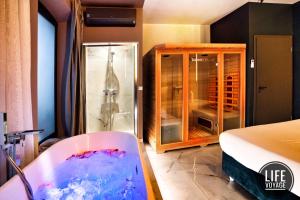 um quarto com uma banheira e um chuveiro em vidro em LIFE VOYAGE & SPA by Life Renaissance em Estrasburgo
