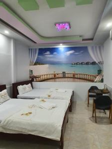 two beds in a room with a painting on the wall at Khách Sạn Trường Thịnh in Ben Tre