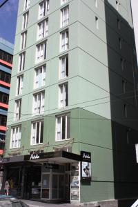 a tall green building on a city street at Astelia Apartment Hotel in Wellington