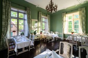 a dining room with white tables and windows at Hotel & Gästehaus Gut Kaden in Alveslohe