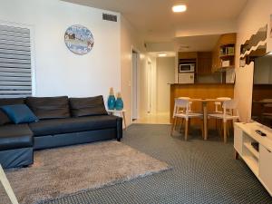 a living room with a black couch and a kitchen at Mooloolaba Beachfront: Superior Resort Apartment in Mooloolaba