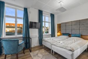 a bedroom with a bed and a chair and windows at Esbjerg BB hotel in Esbjerg