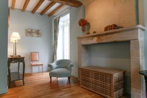 a living room with a fireplace and a chair at Chambres d'hôtes du Bas Manoir in Bretteville-sur-Odon +21 photos