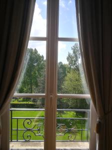 een open raam met uitzicht op een tuin bij Chambres d'Hôtes Le Bas Manoir in Bretteville-sur-Odon