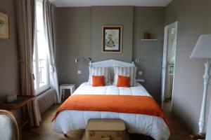 een slaapkamer met een groot bed met oranje kussens bij Chambres d'Hôtes Le Bas Manoir in Bretteville-sur-Odon