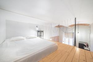 una camera con letto bianco e pavimento in legno di Dizzy Daisy Downtown Apartments a Cracovia