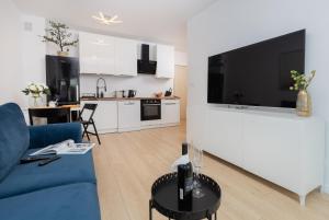 a living room with a blue couch and a kitchen at Nadmorskie Tarasy Gdynia by Renters in Gdynia