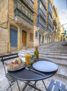 una mesa con un plato de pan y zumo de naranja en Cute and modern duplex apartment in ideal location RCAS1-1, en La Valeta