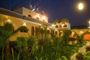 a building with a garden in front of it at night at Janat Elsahara Hotel in Luxor