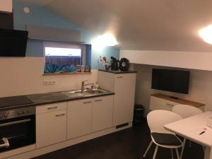 a kitchen with white cabinets and a sink and a table at Haus Bergblick in Gaschurn