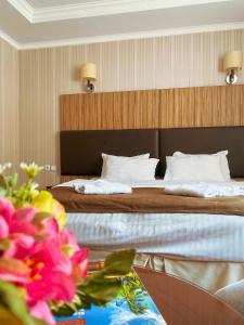 two beds in a hotel room with flowers on a table at Nomad Hotel in Astana