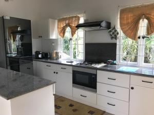 a kitchen with white cabinets and a stove top oven at Residence Monte-Cristo in Anse Boileau