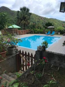 une grande piscine bleue avec une clôture et des chaises dans l'établissement Residence Monte-Cristo, à Anse Boileau