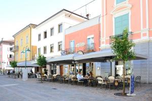 a group of people sitting at tables on a street at Hotel Vittoria in Riva del Garda